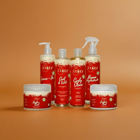 A set of Curly Pouss hair care products including shampoo, conditioner, a spray bottle, a jar of styling mousse, and a no-rinse defining milk, all by JS Organics.
