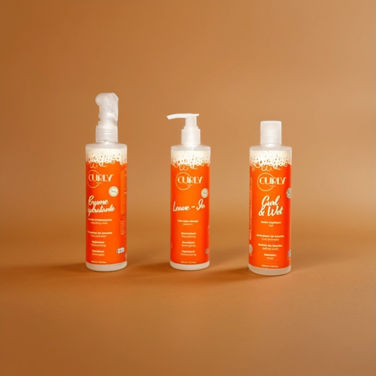 Three orange bottles of Curly Pouss hair products: hydrating cream, leave-in conditioner, and curl & wet gel by JS Organics